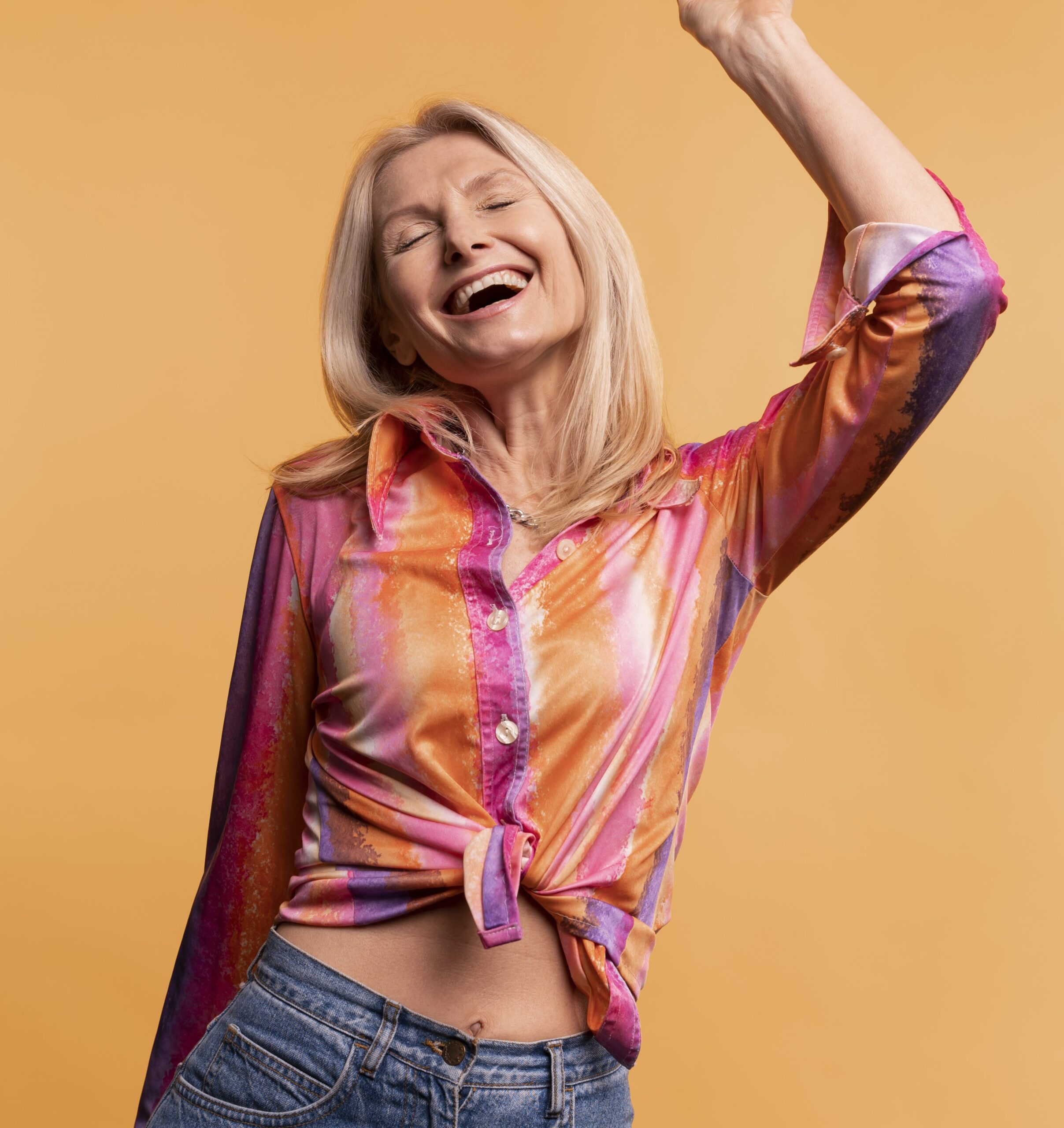 blond-senior-woman-dancing-against-yellow-background